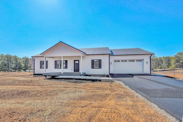 view of front of house with an attached garage, metal roof, and driveway