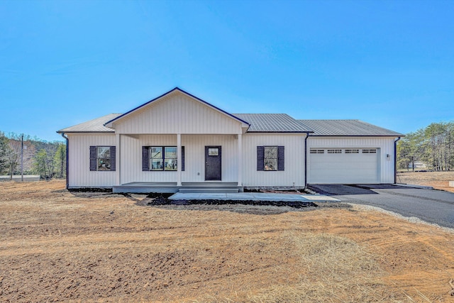 modern inspired farmhouse with a garage, driveway, and metal roof