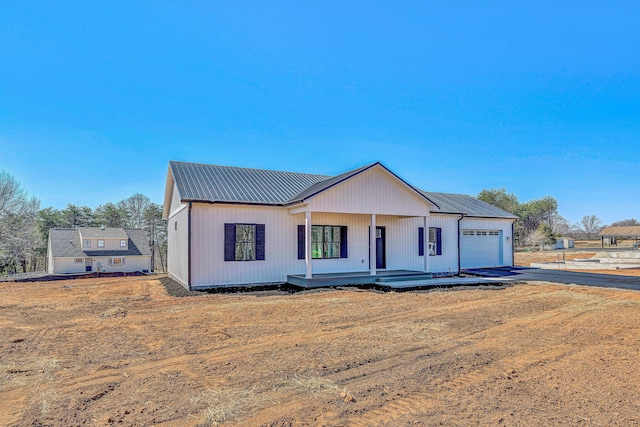 view of front of home featuring a porch, a garage, and metal roof