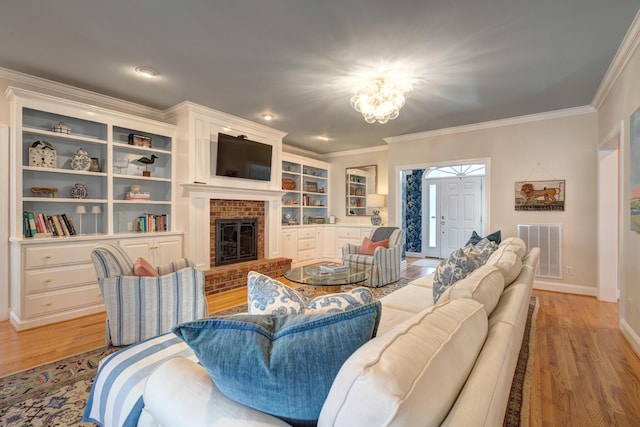 living area featuring light wood-style flooring, a fireplace, visible vents, and ornamental molding