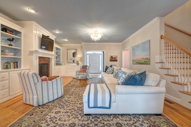 living room with visible vents, stairs, ornamental molding, a fireplace, and light wood-style floors