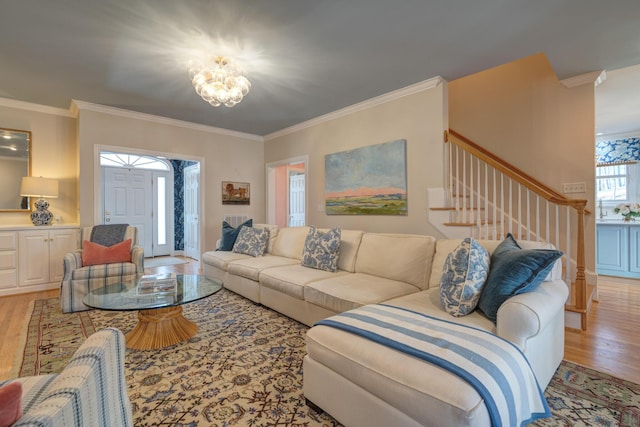 living area featuring a notable chandelier, light wood-style flooring, stairs, and ornamental molding