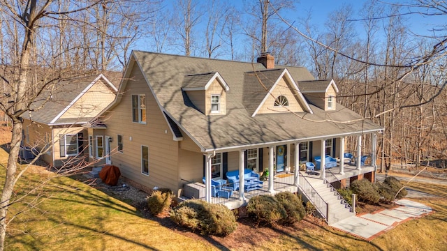 view of front of property with a front yard, central AC unit, a porch, a shingled roof, and a chimney