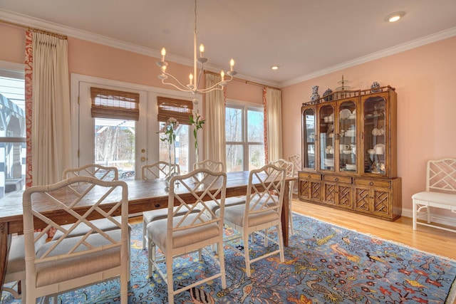 dining space with a notable chandelier, wood finished floors, french doors, crown molding, and baseboards