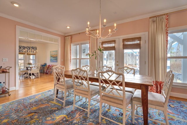 dining room featuring crown molding, a notable chandelier, french doors, and light wood finished floors