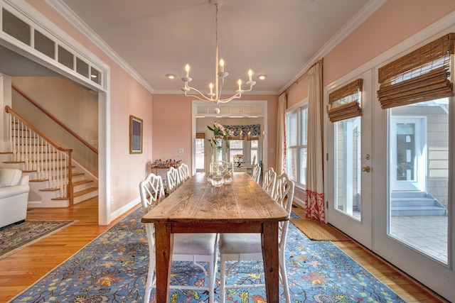 dining room featuring french doors, wood finished floors, an inviting chandelier, and ornamental molding