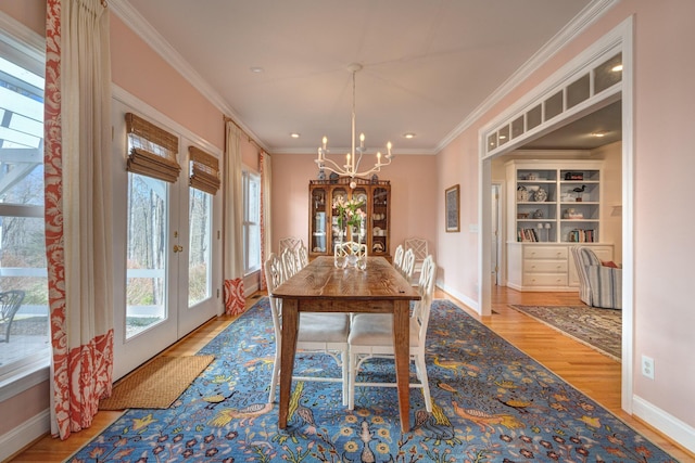 dining space featuring wood finished floors, french doors, an inviting chandelier, crown molding, and baseboards