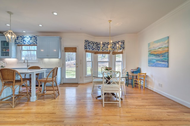 dining space featuring crown molding, a notable chandelier, baseboards, and light wood-type flooring