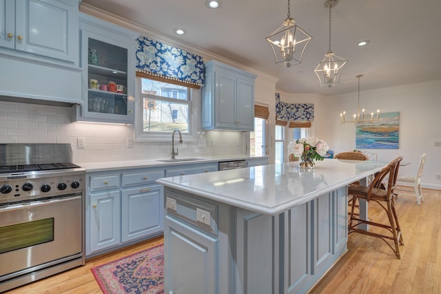 kitchen with a sink, blue cabinetry, appliances with stainless steel finishes, an inviting chandelier, and light countertops