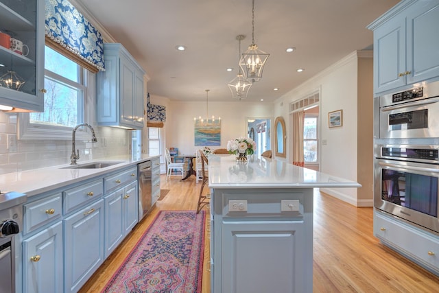 kitchen featuring an inviting chandelier, a sink, light countertops, appliances with stainless steel finishes, and backsplash