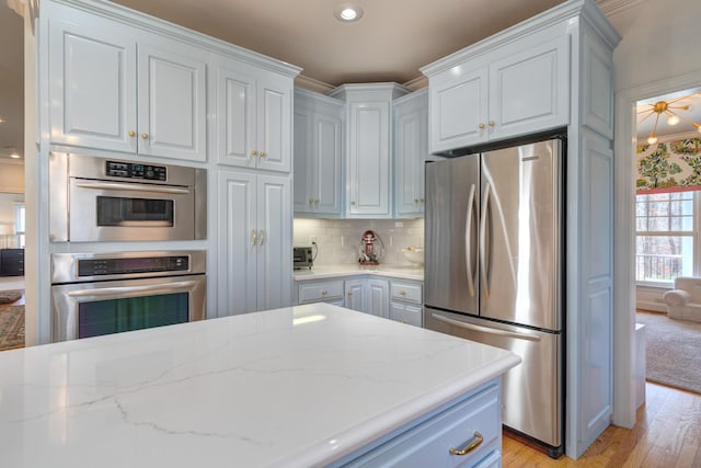 kitchen featuring stainless steel appliances, white cabinets, decorative backsplash, and light wood finished floors