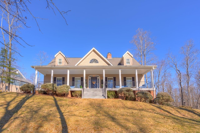 view of front of property with a chimney, covered porch, and a front yard