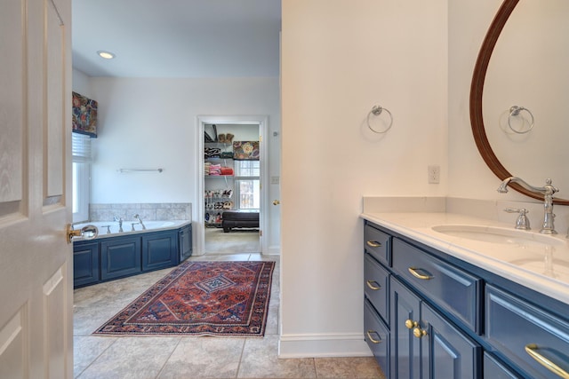 bathroom featuring vanity, baseboards, tile patterned flooring, a walk in closet, and a bath