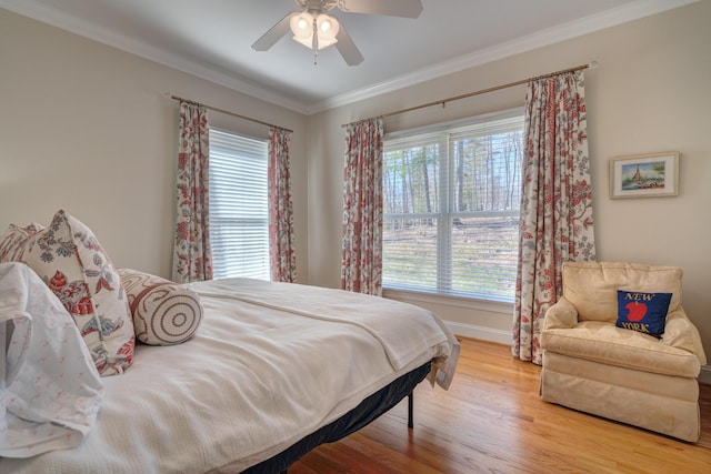 bedroom with baseboards, wood finished floors, ornamental molding, and a ceiling fan