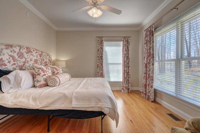 bedroom featuring a ceiling fan, baseboards, visible vents, ornamental molding, and light wood-style floors