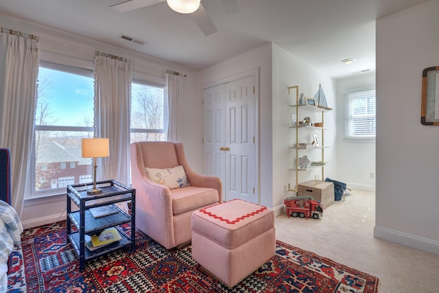 living area featuring visible vents, baseboards, carpet floors, and ceiling fan