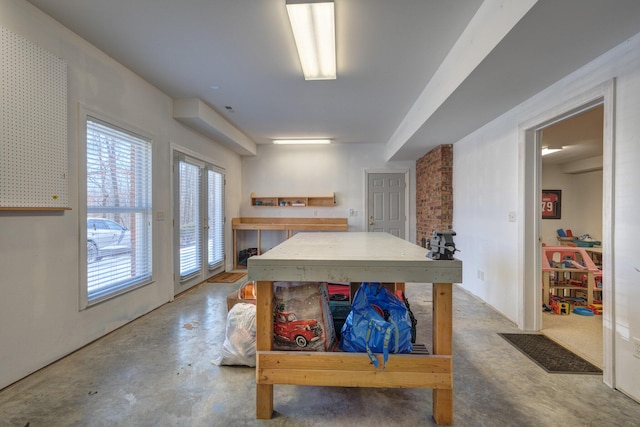 game room with a workshop area, unfinished concrete flooring, and visible vents