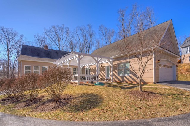 view of front of home with driveway, a pergola, a front yard, a garage, and a chimney