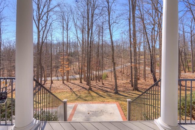 wooden deck with a forest view and a patio