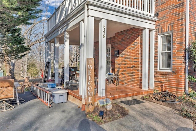 doorway to property featuring a balcony and brick siding