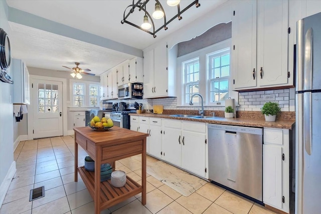 kitchen with a sink, appliances with stainless steel finishes, tasteful backsplash, and white cabinets