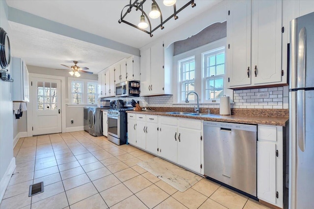 kitchen featuring visible vents, washer / clothes dryer, a sink, appliances with stainless steel finishes, and dark countertops