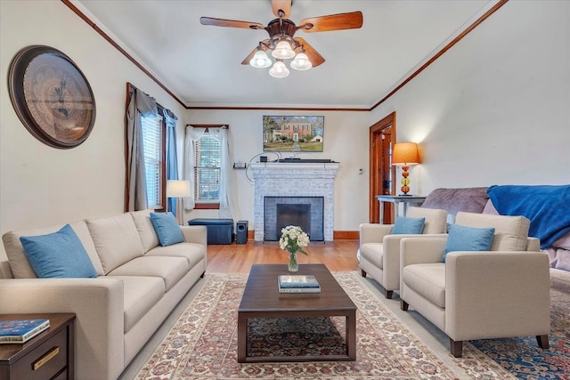 living room with crown molding, a brick fireplace, light wood finished floors, and ceiling fan