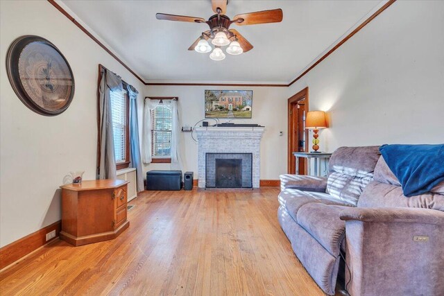 living area featuring a fireplace, baseboards, crown molding, and light wood-style floors