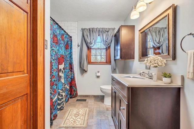 full bath with vanity, toilet, a textured ceiling, stone finish floor, and a shower with curtain