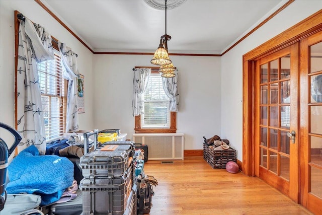 interior space with wood finished floors, baseboards, radiator heating unit, ornamental molding, and french doors