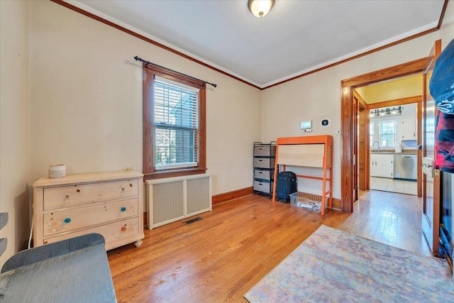 office area featuring a healthy amount of sunlight, radiator, ornamental molding, and wood finished floors