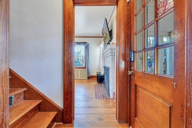 corridor featuring crown molding, stairway, and light wood finished floors