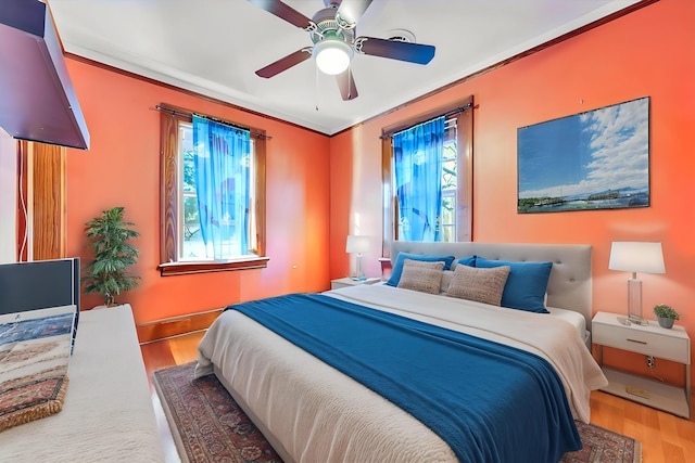 bedroom featuring baseboards, ornamental molding, a ceiling fan, and wood finished floors