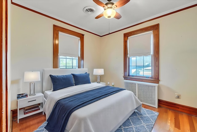 bedroom featuring visible vents, ornamental molding, radiator heating unit, and wood finished floors