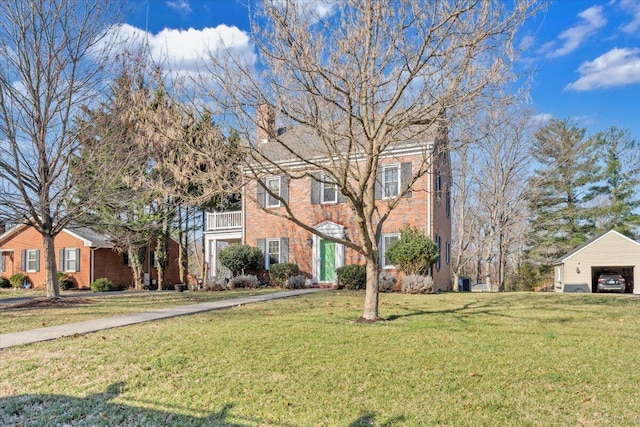 colonial home with a front lawn, brick siding, and a detached garage