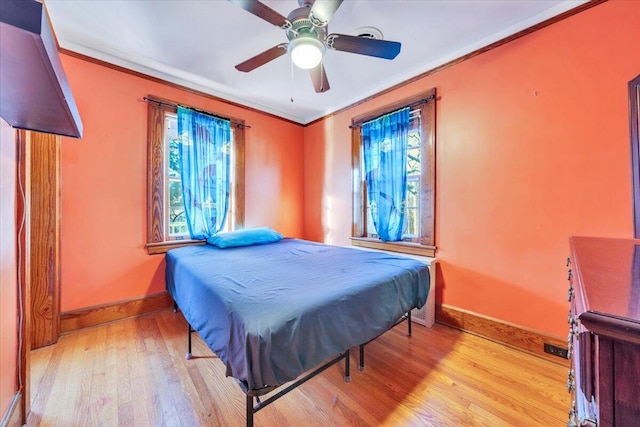 bedroom featuring ceiling fan, light wood-style flooring, baseboards, and ornamental molding