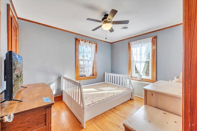 bedroom with multiple windows, light wood-style floors, and ornamental molding