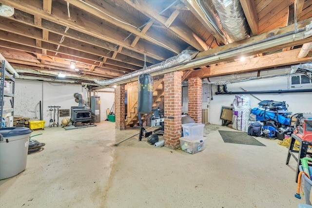 unfinished basement featuring a wood stove and water heater