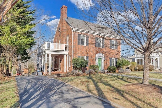 view of front of home featuring a front lawn, brick siding, and a chimney