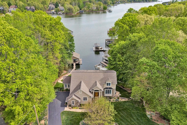 view from above of property featuring a nearby body of water and a heavily wooded area