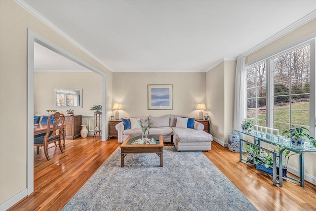 living area with baseboards, hardwood / wood-style floors, and crown molding