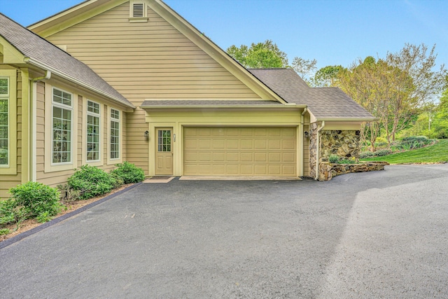 view of front of property featuring an attached garage, roof with shingles, and driveway