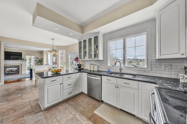 kitchen featuring a sink, backsplash, a peninsula, a fireplace, and dishwasher