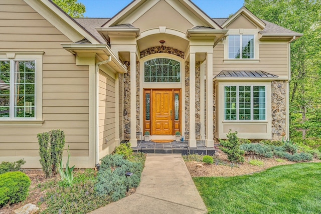 view of exterior entry featuring stone siding and a standing seam roof