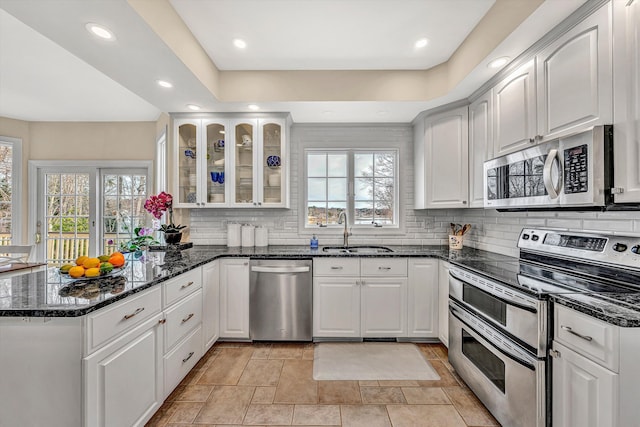 kitchen featuring a healthy amount of sunlight, a peninsula, stainless steel appliances, and a sink