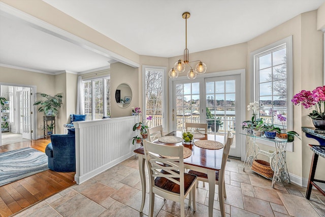 dining space with stone tile floors, a chandelier, baseboards, and ornamental molding