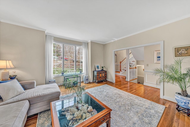 living area featuring stairs, ornamental molding, wood finished floors, and baseboards
