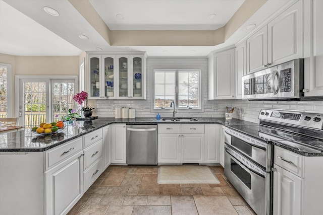 kitchen with appliances with stainless steel finishes, a sink, a peninsula, backsplash, and recessed lighting