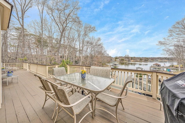 deck featuring outdoor dining space, area for grilling, and a water view