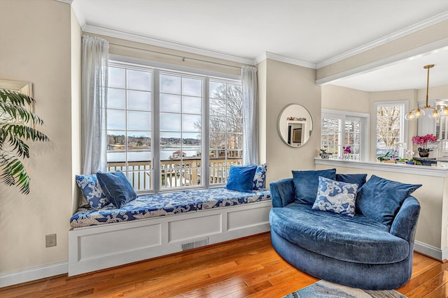 sitting room with wood-type flooring, crown molding, healthy amount of natural light, a water view, and a chandelier